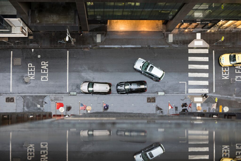 looking-down-at-a-busy-street-in-the-city-with-cars-moving-people-walking-on-the-sidewalk-keep-clear